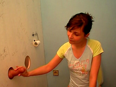 Amy sitting on a toilet when she sees a rod coming out of a glory-hole