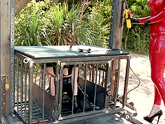 Submissive girl in shiny latex spanked by mistress outdoors