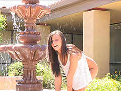 Busty brunette beauty gets wet in a fountain and rubs her shaved twat